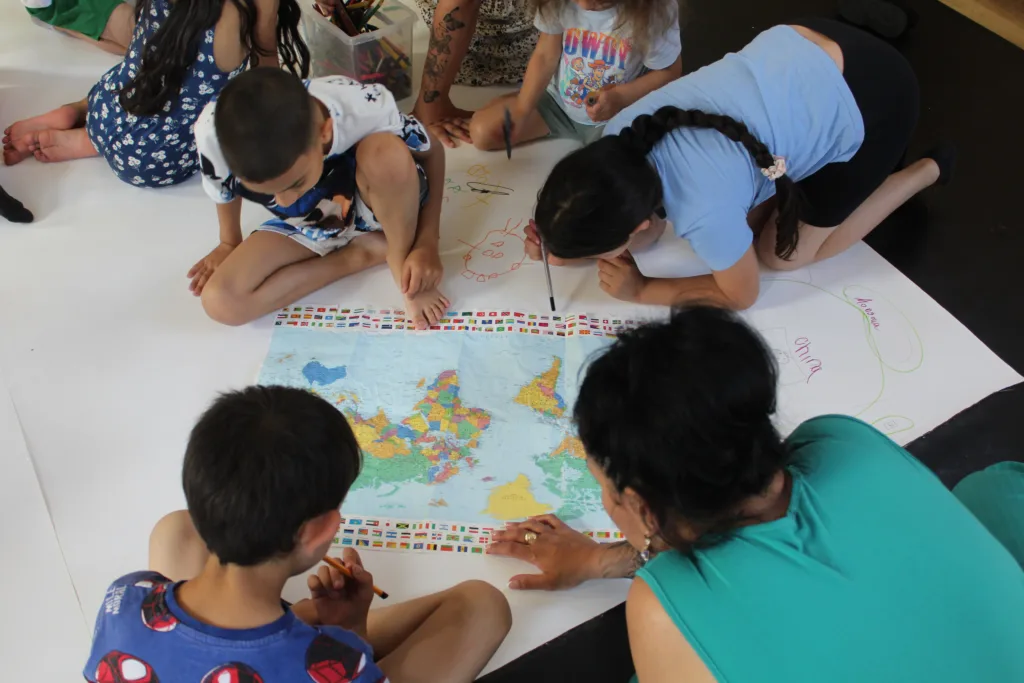 A group of children leaning over a map of the world